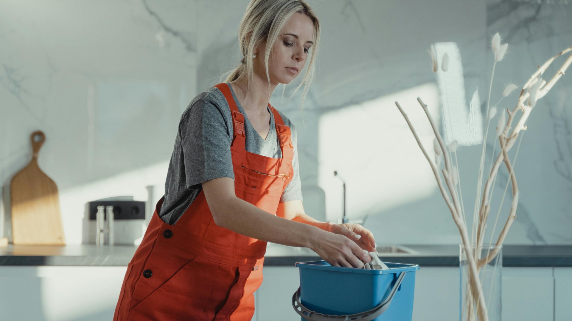 A house cleaner wiping a counter in a bright home