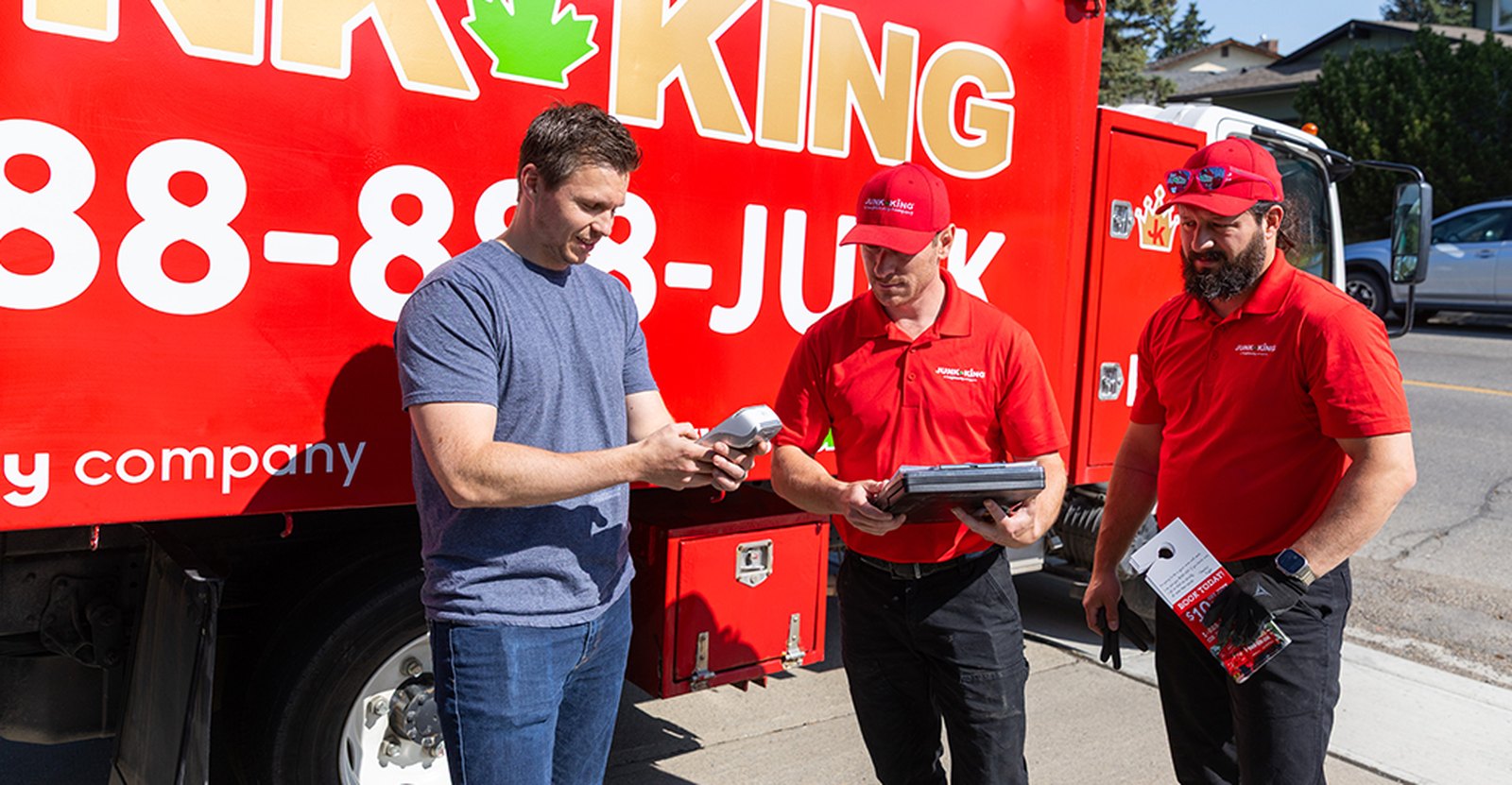 A Junk King crew checking in a customer beside their truck