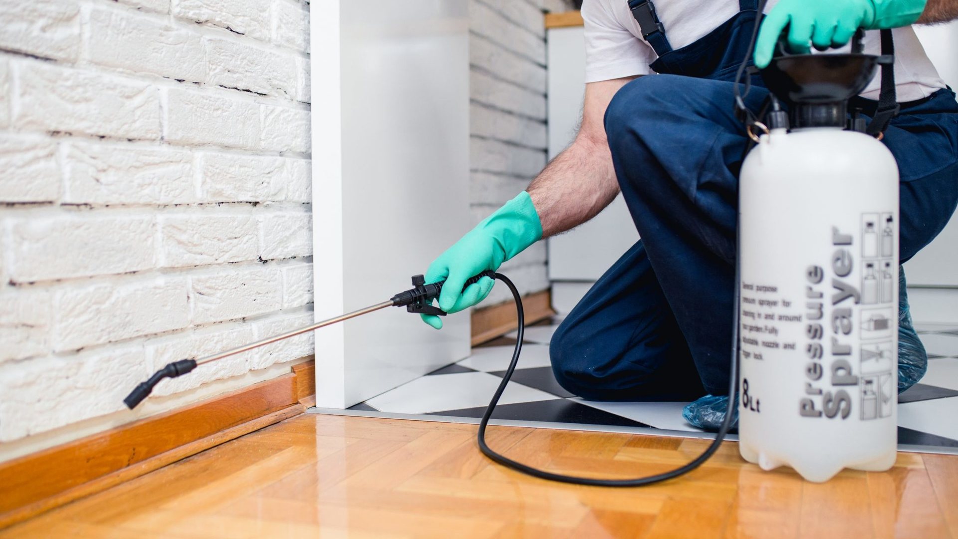 A pest control technician spraying along a home's baseboard